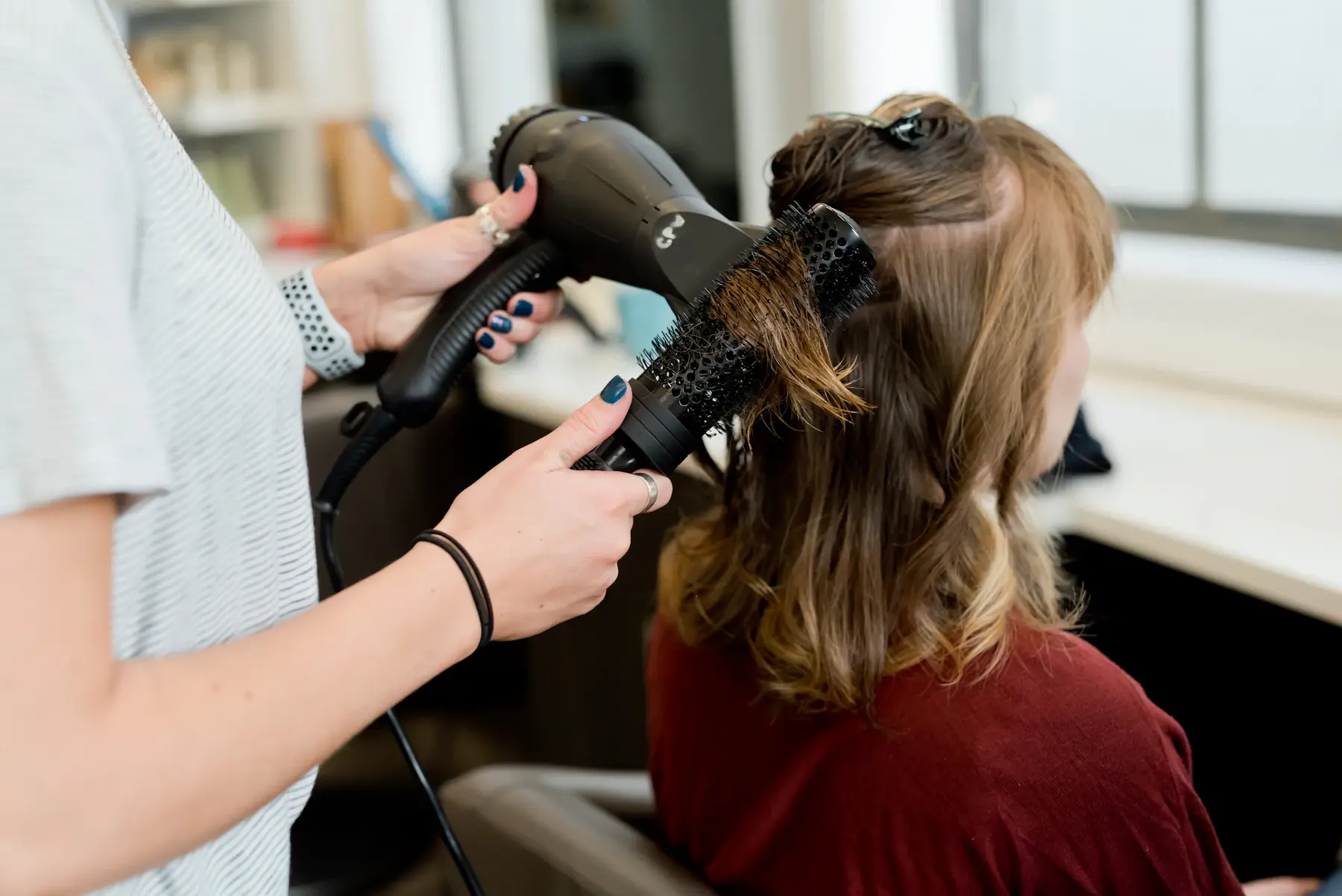 A stylist finishing a look with a dryer and round brush